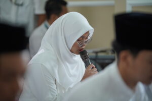 Seorang siswi sedang membaca Al-Qur'an, pandangannya terfokus pada mushaf di hadapannya