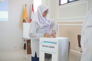 Potret seorang siswa sedang memasukkan surat suara ke dalam kotak suara