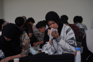 Seorang anak fokus mewarnai motif batik di atas pouchnya